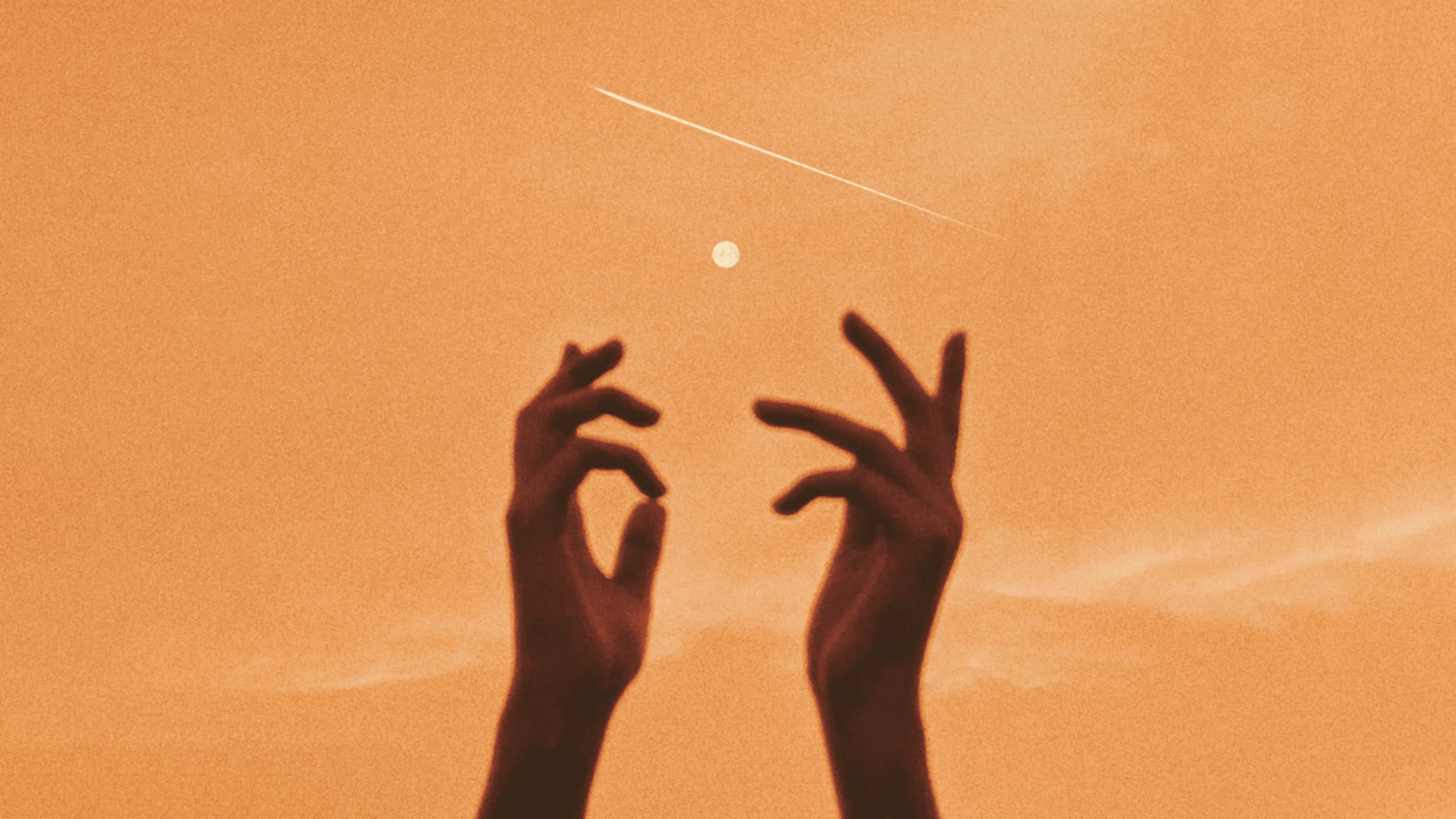 Dos manos recortadas sobre un cielo naranja al atardecer