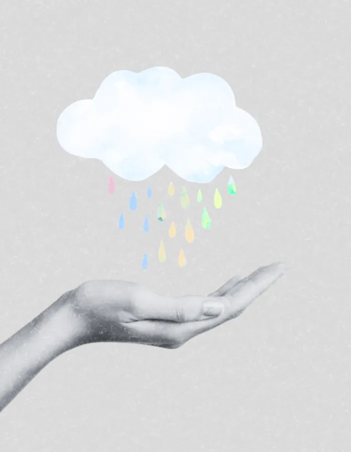 Mano que sostiene una nube de la que caen gotas de colores