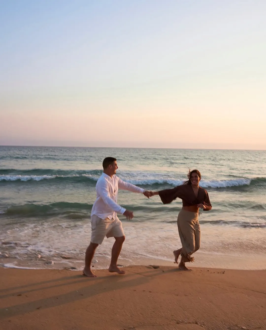 Pareja paseando por la orilla del mar al atardecer